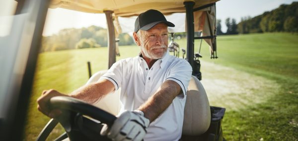 Senior man driving his golf cart on a fairway